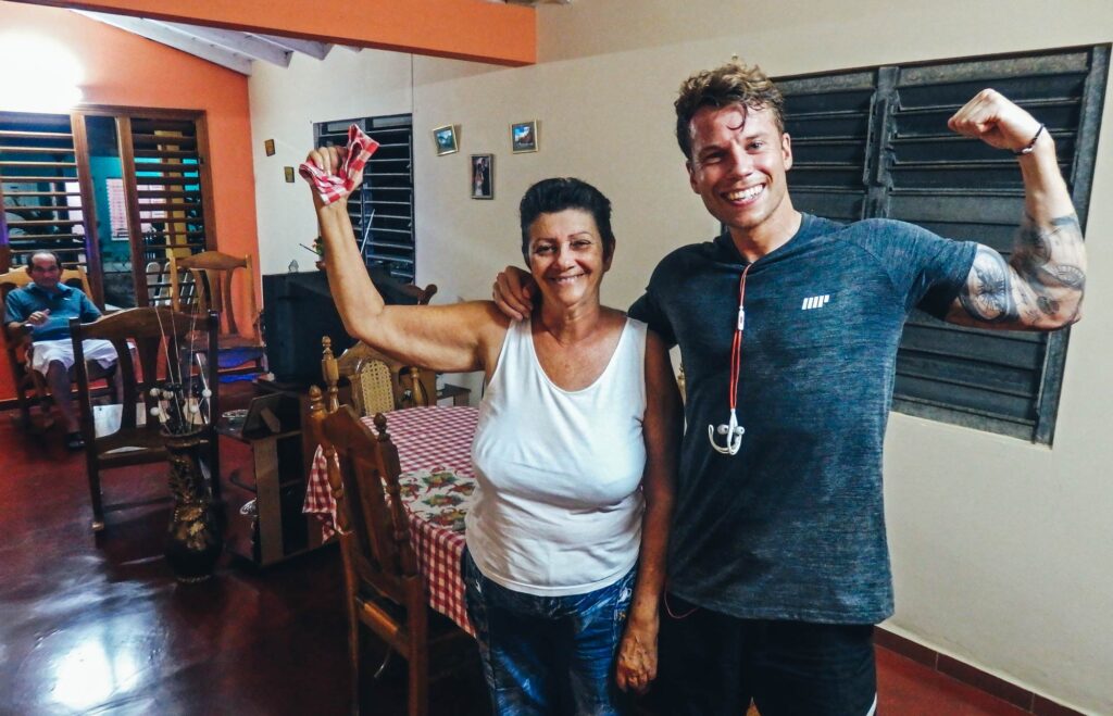 One awesome reason to backpack Vinales. A man stands with an older Cuban women flexing his bicep and smiling