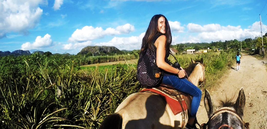 One awesome reason to backpack Vinales. A girl sits on the back of a horse during the gin tour